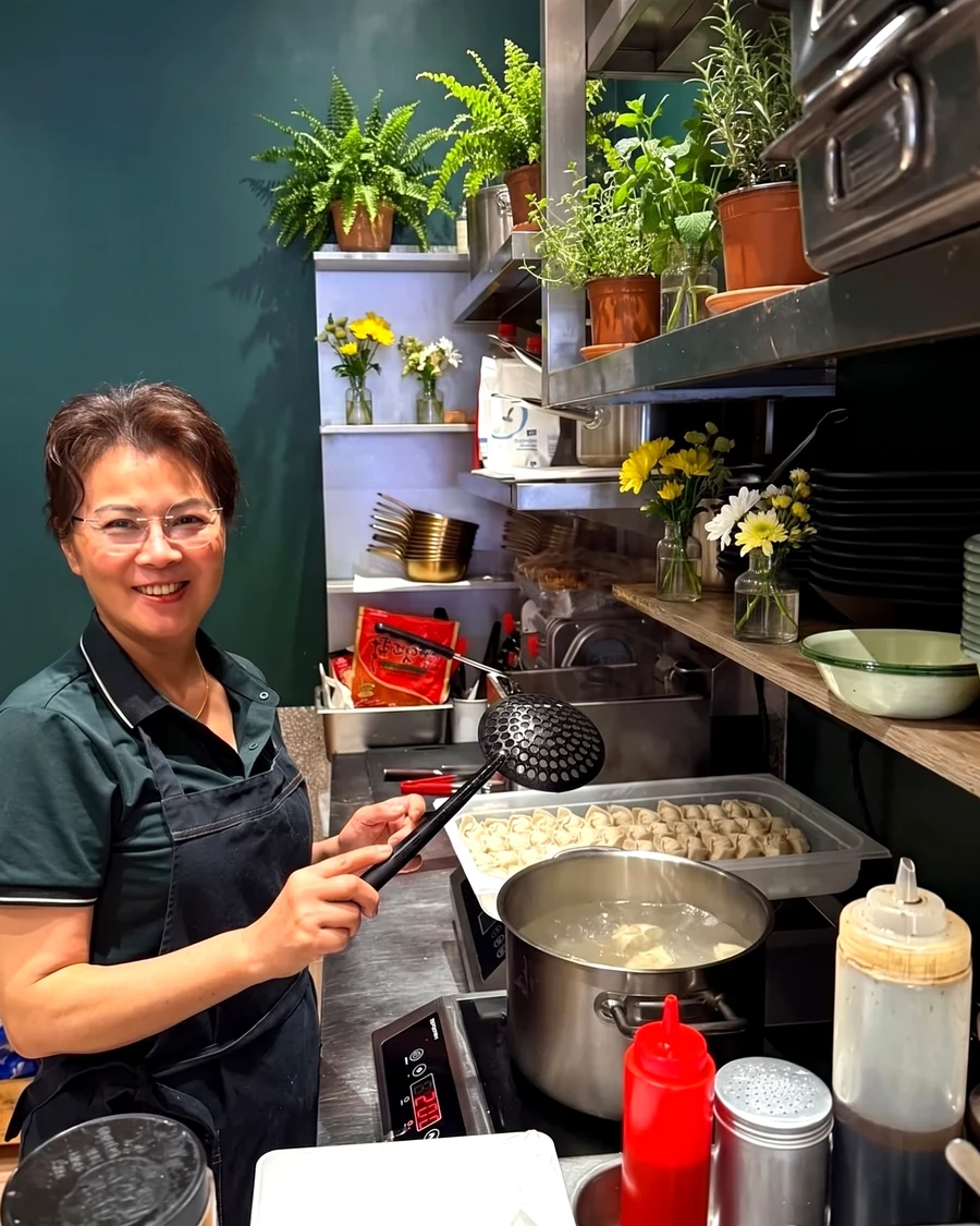 Frau Wang faltet frische Dumplings in der offenen Küche